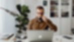 A man on a video call drinking coffee, representing virtual alcohol support during home-based rehab.