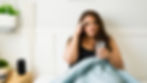 A person with hangover sitting on a bed with water after drinking.
