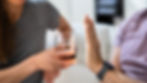 A person politely declining a glass of alcohol at a social event.