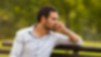 A man sitting on bench during the first week of quitting drugs, appearing reflective.