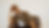 A blurred image of a person holding their head with both hands, eyes closed, and motion blur emphasizing stress or movement.